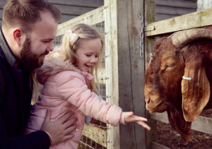 Girl and father at barleylands feeding a goat