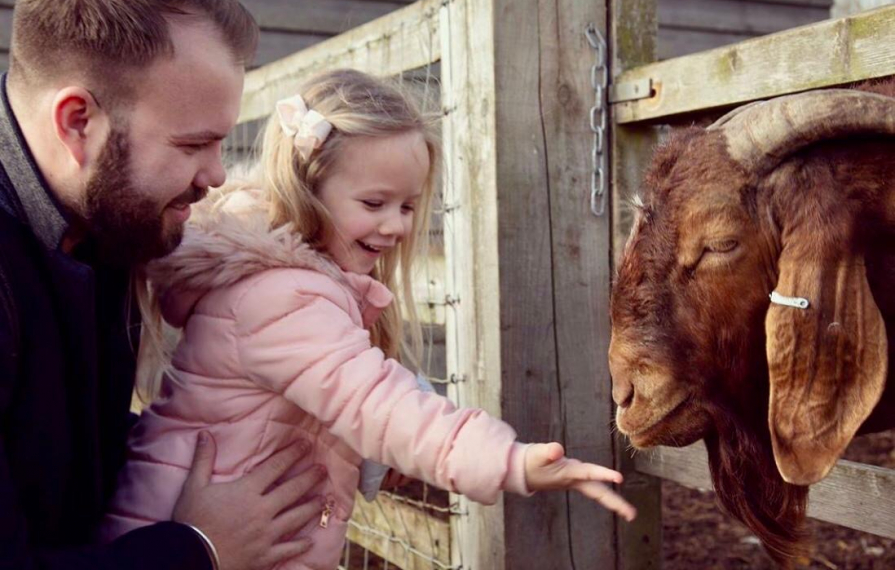 Girl and father at barleylands feeding a goat